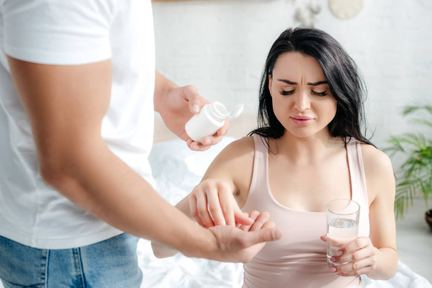 husband giving pills to pregnant wife with pain in bedroom  - Fotó, kép