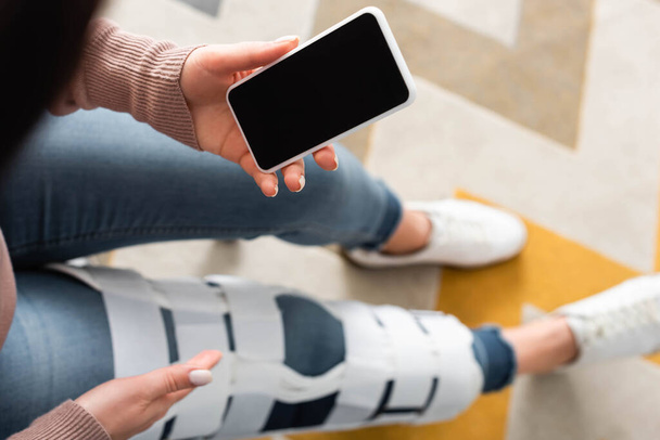 обрезанный вид женщины с ногой скобки, имеющие онлайн консультации с врачом на смартфоне с пустым экраном
 - Фото, изображение