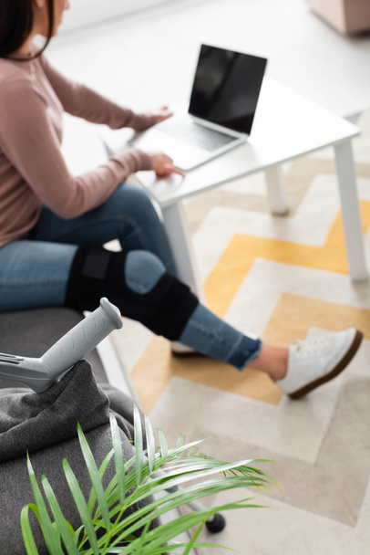 селективный фокус женщины со сломанной ногой, имеющей онлайновую консультацию с врачом на ноутбуке дома
 - Фото, изображение