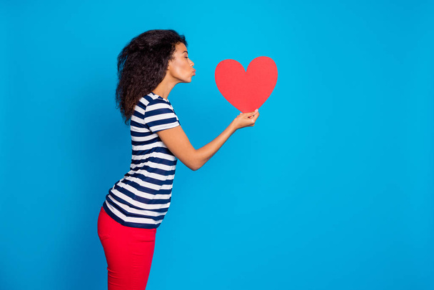 Side profile photo of tender soft cute adorable girlfriend kissing big red heart inspired by her love near empty space wearing striped t-shirt isolated vivid color blue background - Foto, Bild