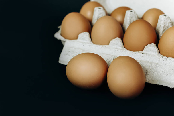 huevos de pollo en una caja de papel gris sobre un fondo negro
 - Foto, Imagen