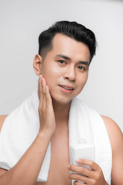 Asiático homem no banheiro aplicando loção facial
 - Foto, Imagem