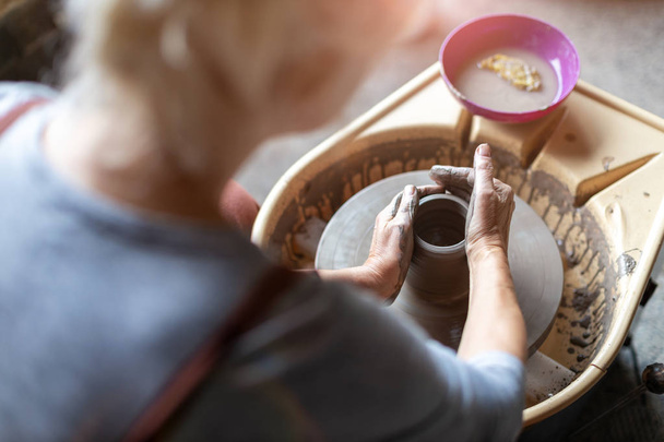Donna anziana che fa lavorare la ceramica con la ruota del vasaio
 - Foto, immagini