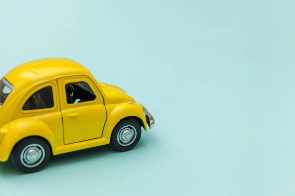 Жовтий старовинний ретро іграшковий автомобіль ізольований на синьому пастельному барвистому фоні
 - Фото, зображення