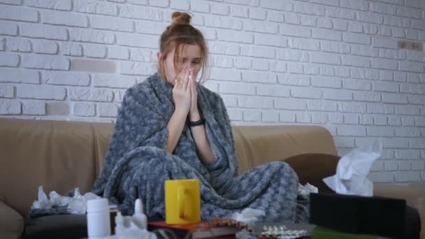 Młoda kaukaska kobieta siedząca na kanapie z gorączką i katarem używa aerozolu do nosa w domu. Zamknij się..  - Materiał filmowy, wideo