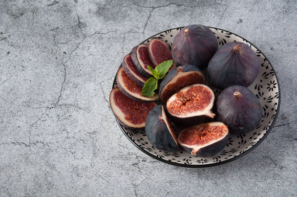 Ripe slices of figs on a light background. Grains of a fruit inside on a cut. Vitamin-rich fruit. Healthy nutrition, ingredients for dishes. Wine berry, Carian ficus. - Photo, Image