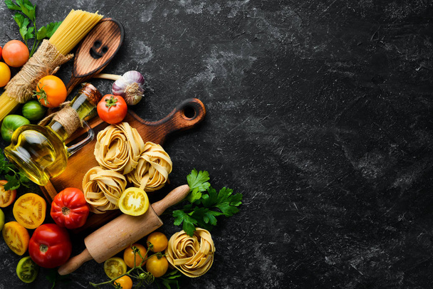 Dry pasta, tomatoes, greens, oil and ingredients. Italian traditional cuisine. Fresh vegetables. Top view. Free space for your text. - Photo, image