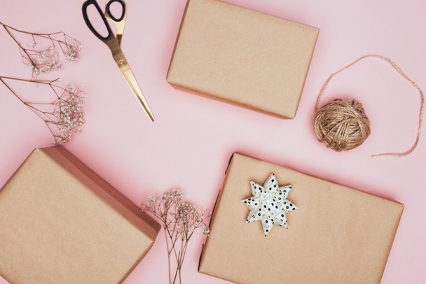 vista superior de las cajas de regalo de Navidad artesanales con tijeras y flores, aisladas en rosa
 - Foto, Imagen