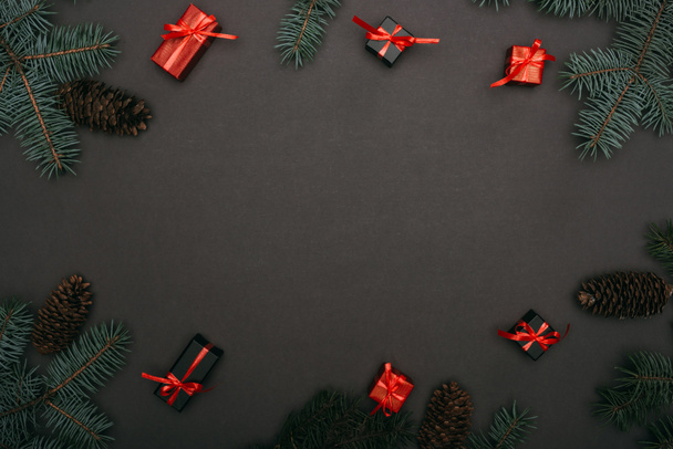 Noel hediyelerinin en üst görüntüsü ladin dalları ve siyah üzerinde çam kozalakları olan kutular - Fotoğraf, Görsel