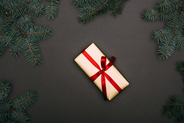 Top pohled na vánoční dárek se smrkovými větvemi na černé - Fotografie, Obrázek