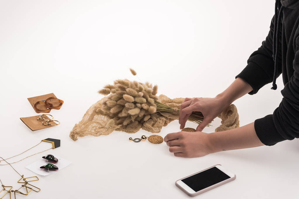visão parcial do fotógrafo comercial fazendo composição com flora e jóias para fotografia comercial no smartphone em branco
 - Foto, Imagem