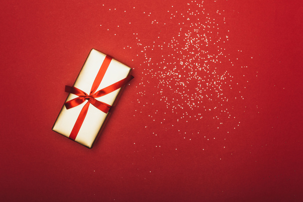 vue du dessus d'un cadeau de Nouvel An avec confettis dorés sur rouge
 - Photo, image