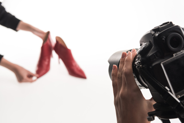 visão recortada de fotógrafos que fazem sessão de fotos comerciais de sapatos de salto vermelho feminino no branco
 - Foto, Imagem