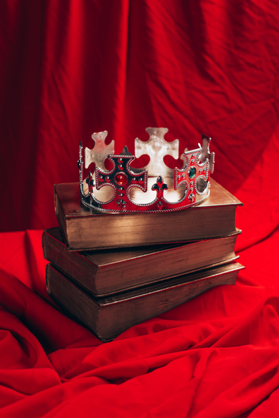 ancient silver crown with gemstones on books on red cloth - 写真・画像