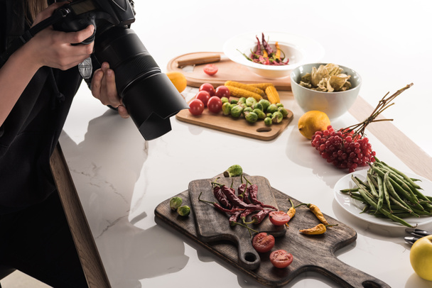 bijgesneden beeld van vrouwelijke fotografe die voedselcompositie maakt voor commerciële fotografie en foto 's maakt op digitale camera  - Foto, afbeelding