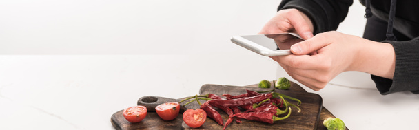 zugeschnittene Ansicht eines Fotografen, der Nahrungsmittelkompositionen für kommerzielle Fotografie auf dem Smartphone herstellt - Foto, Bild