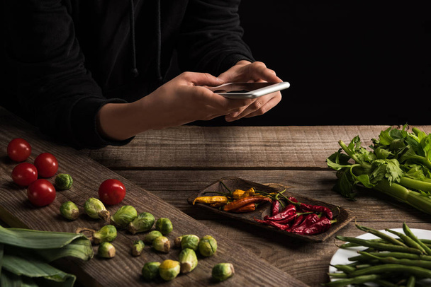 καλλιεργημένη άποψη του φωτογράφου που κάνει σύνθεση τροφίμων για την εμπορική φωτογραφία σε smartphone σε ξύλινο τραπέζι - Φωτογραφία, εικόνα