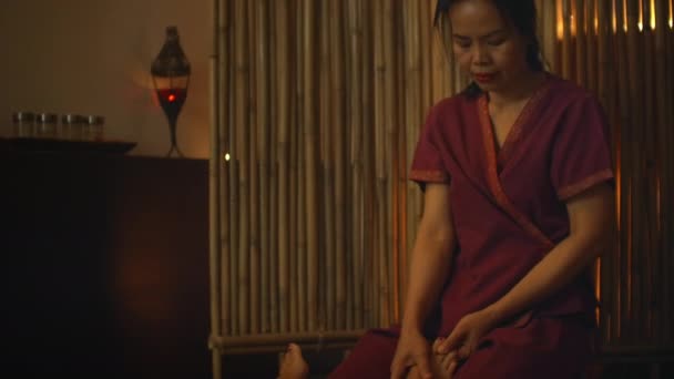 Asian Woman performs Traditional Thai Massage to beautiful European Woman. Rehabilitation and Treatment after Injuries with the help of Massage. Relax and Rest from massage of Legs, Arms and Back. - Felvétel, videó