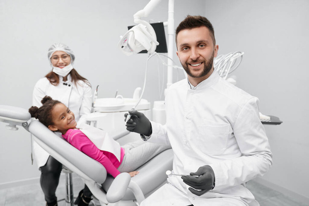 Dentist keeping equipment while child lying on dentist chair - Fotoğraf, Görsel