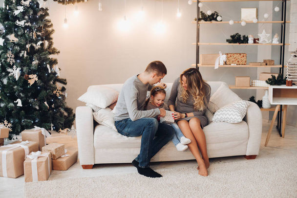 Family with child opening Christmas present.Christmas tree. - Foto, imagen