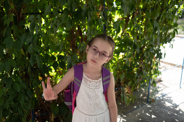 Colegiala con mochila violeta y gafas moradas. Chica en un vestido blanco, con gafas en otoño
. - Foto, imagen