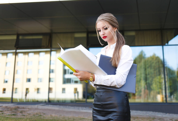 Young business woman with a displeased facial expression examines documents in detail - 写真・画像