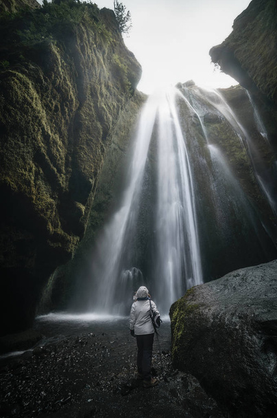 Женщина, смотрящая на водопад Глюфрабуй внутри пещеры в Айселе
 - Фото, изображение