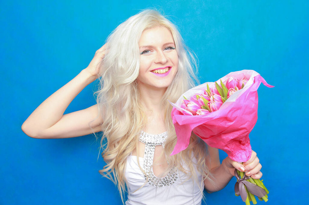 horké šťastný druh žena v bílém těsné módní šaty s růžovým tulipánem květiny na modrém pozadí studia. - Fotografie, Obrázek