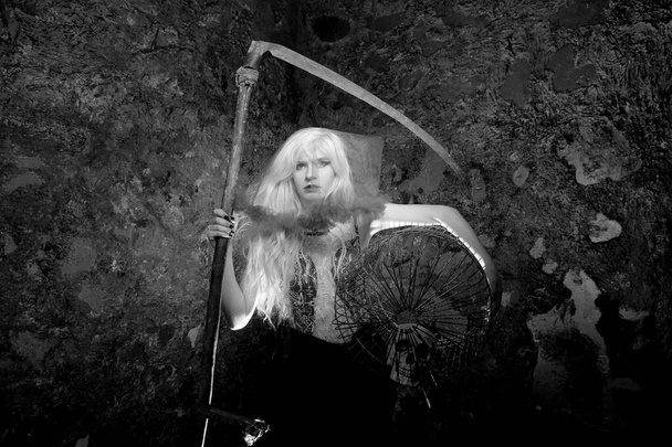 gloomy girl with a large cage and a scythe on a dark background, black and white photo - Photo, Image
