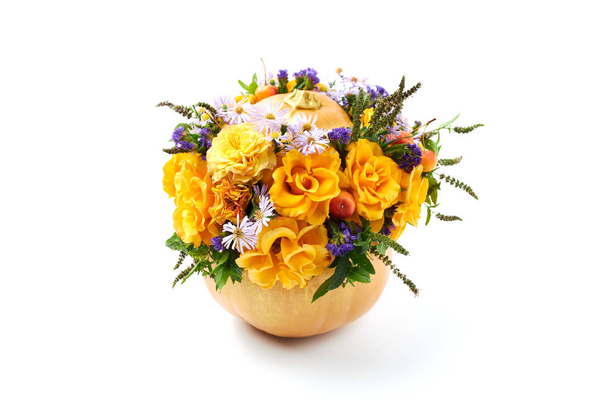 Composición de calabaza naranja madura rellena de flores amarillas sobre un fondo blanco
 - Foto, Imagen