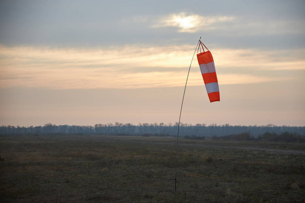 Indicador de velocidad y resistencia al viento en el aeródromo en forma de manga cónica a rayas
 - Foto, Imagen