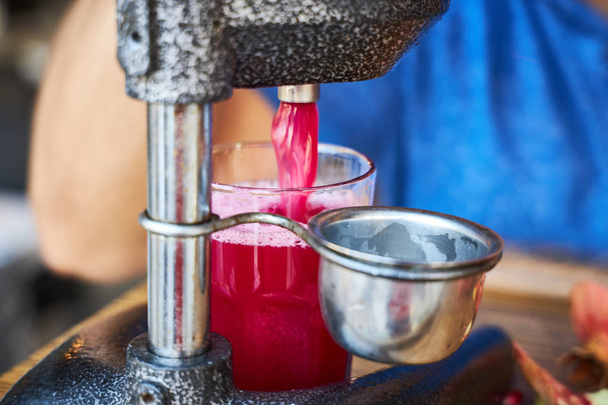 Street vendor squeezes juice from ripe pomegranates - Photo, Image