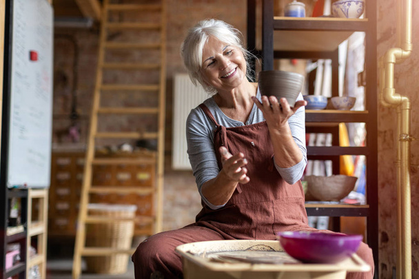 Elderly woman making ceramic work with potter's wheel - Fotoğraf, Görsel