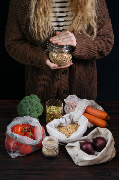 Самка держит многоразовый банк с зерном среди органических продуктов питания в е
 - Фото, изображение