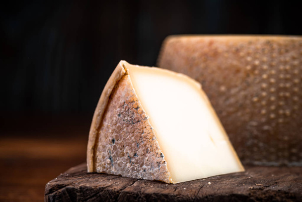 Slice of Hard Matured Cheese from Whole Cheese Wheel - 写真・画像