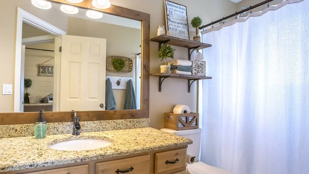 Marco panorámico Interior del baño en casa con zona de tocador e inodoro contra pared beige
 - Foto, Imagen