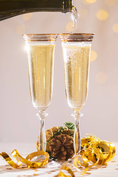 Pouring champagne wine into glasses over blur spots light background ready to bring in the New Year - Photo, Image