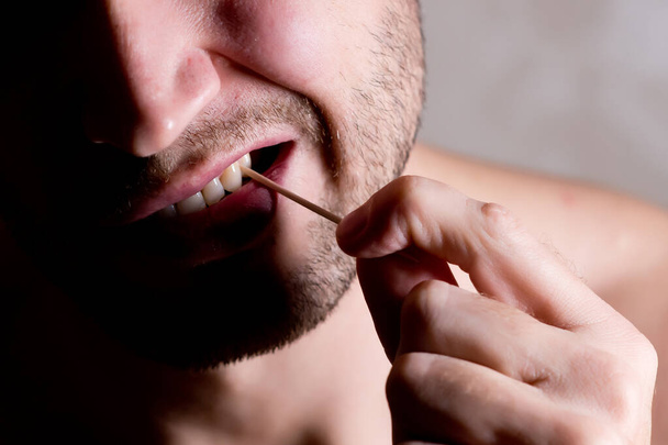 man cleans the space between the teeth with a toothpick, close up - Zdjęcie, obraz