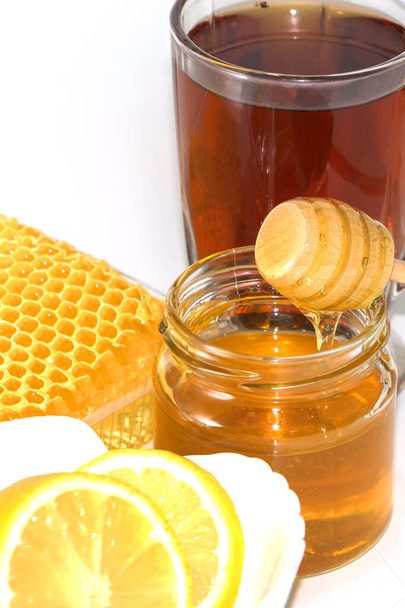 Honing op de achtergrond van honingraat. Honing in een glazen pot en honingraat - Foto, afbeelding