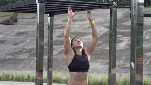 woman exercising on monkey bar during obstacle course. Female athlete crossing monkey bar. Woman hanging at high or horizontal bar - Filmati, video