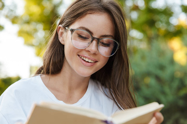 Smiling young girl reading a book - Fotoğraf, Görsel