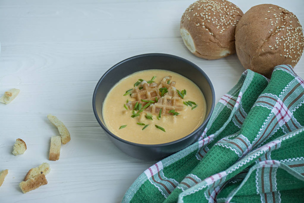 Σούπα τυριού με κράκερ, βότανα και φέτα. Κρέμα σούπας σερβίρεται σε λευκό πιάτο. Λευκό φόντο. - Φωτογραφία, εικόνα