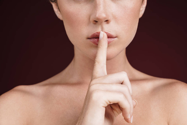 Cropped image of shirtless young woman holding finger at her lip - Foto, immagini