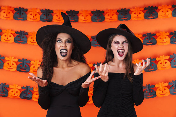 Image of furious witch women in black halloween costume and make - Fotó, kép