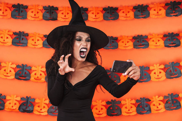 Image of witch girl in halloween costume screaming while taking  - Foto, Imagem
