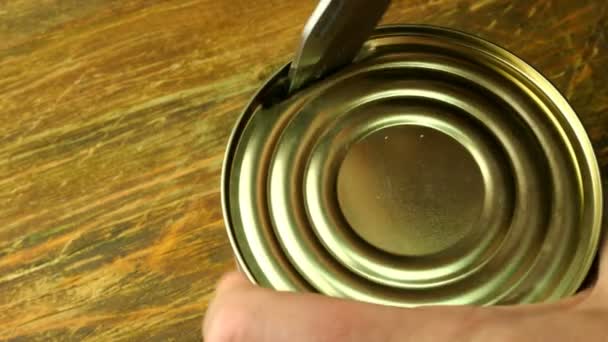 缶詰の肉人間の手は、木製のテーブルの上にキッチンナイフの点で、缶に缶詰のシチューを開くことができます。閉鎖. - 映像、動画