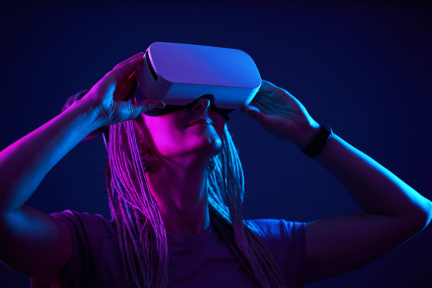 A mulher está usando fones de ouvido de realidade virtual. Retrato de estúdio luz néon. - Foto, Imagem