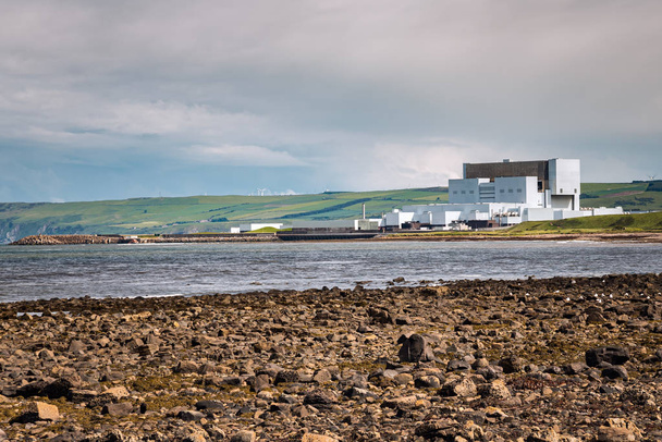 Φωτογραφία ενός πυρηνικού σταθμού στην ακτή με καλλιεργημένους λόφους στο παρασκήνιο σε μια συννεφιασμένη ανοιξιάτικη ημέρα. Dunbar, Σκωτία, Ηνωμένο Βασίλειο. - Φωτογραφία, εικόνα