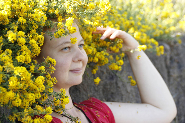 Retrato centrado en los colores de una joven caucásica pelirroja rodeada de brillantes flores amarillas
. - Foto, imagen