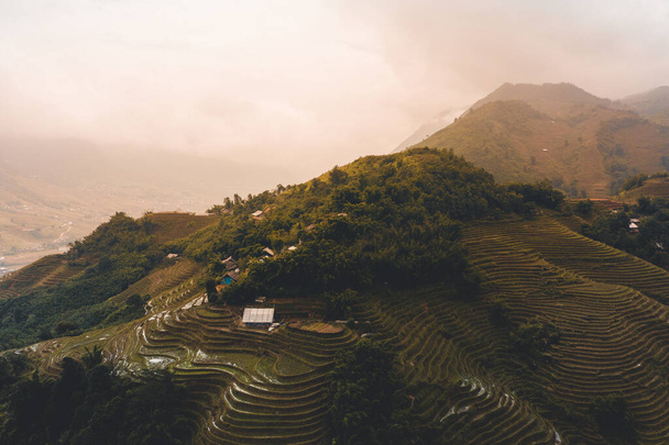 Beautiful Aerial shot of sunrise over the rice terraces of Sapa in North Vietnam during Autumn as the clouds pass over the peaks of the mountains - Foto, afbeelding